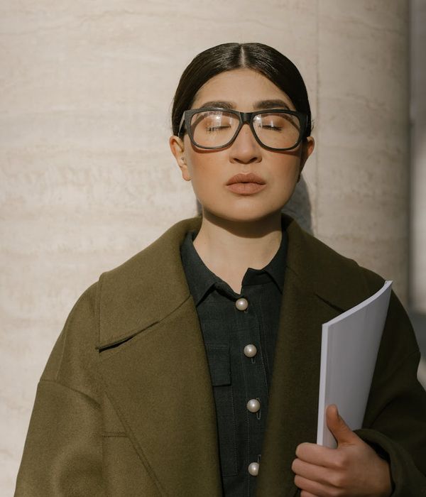 A serene woman practicing eye focus exercises in a modern office.